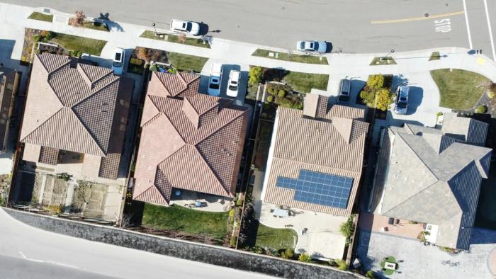 Top-down view of homes in a neighborhood. One house has solar panels on the roof.
