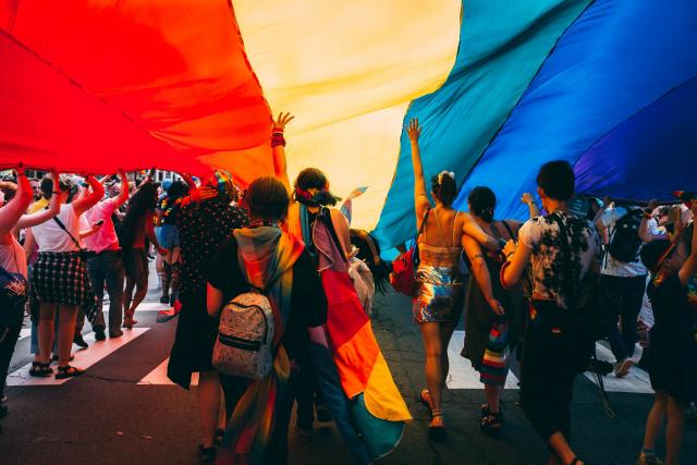 People on a street under a large rainbow flat