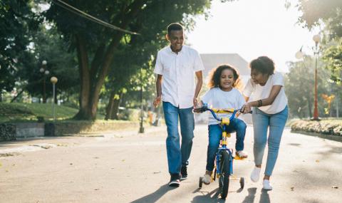 Family helping daughter ride a bike