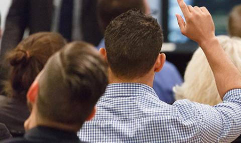 student in crowd with hand raised