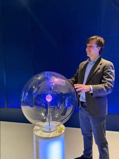 James Marcucci stands in front of a glass ball with sparks inside to simulate electricity at the museum