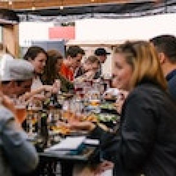 A group of people sitting at a long table, eating and drinking.