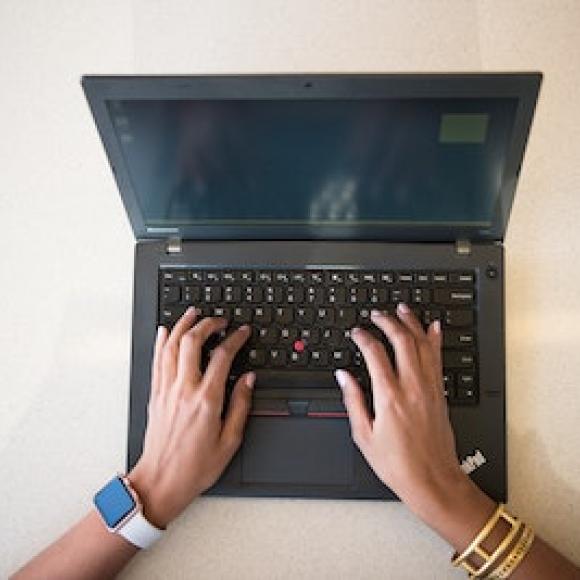 A laptop computer shown from above, with someone's hands typing on it.