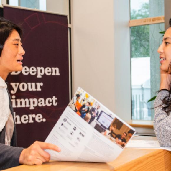 women talk at booth at admissions fair