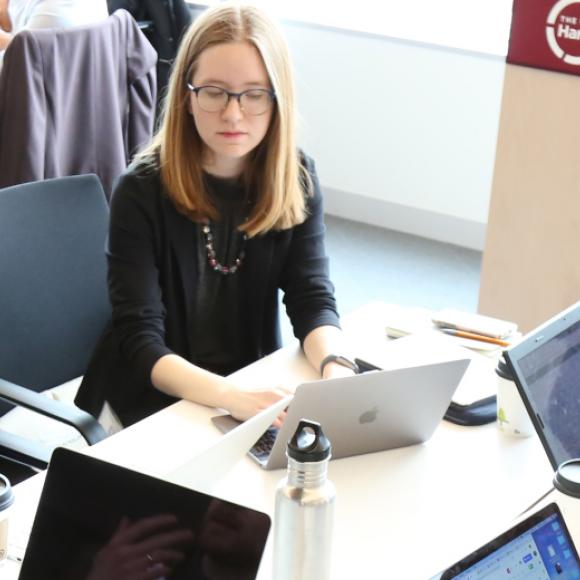A student works on her laptop with a group