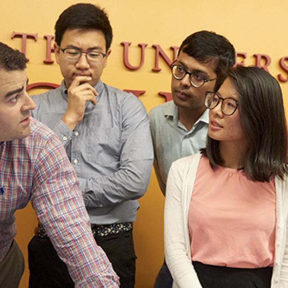 five students stand in front of a uchicago banner collaborating