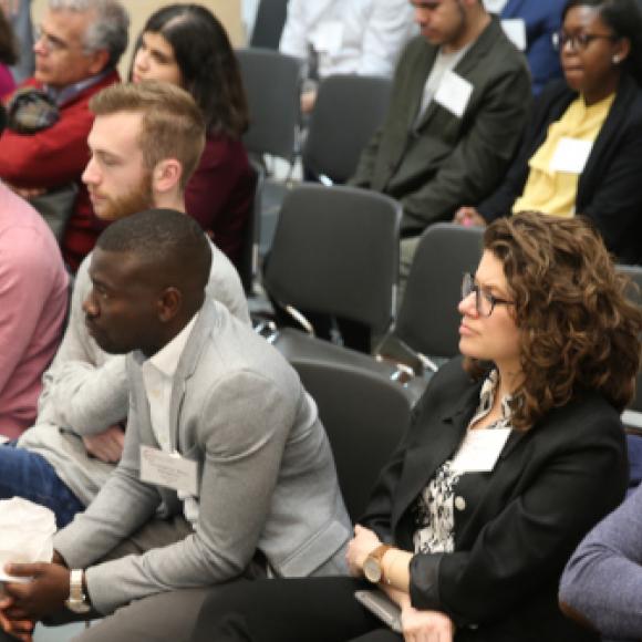Students sit in a row in an auditorium and listen to a presentation