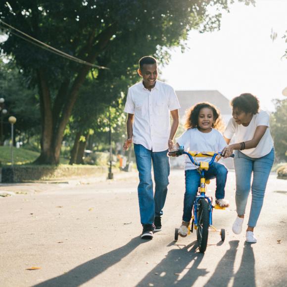 Family helping daughter ride a bike