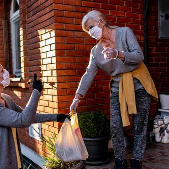 A woman accepting a food delivery from another woman