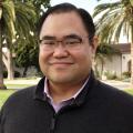 Richard Chang smiling in a dark sweater with palm trees behind him