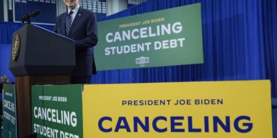 Joe Biden giving a speech in front of 'Canceling Student Debt' signs